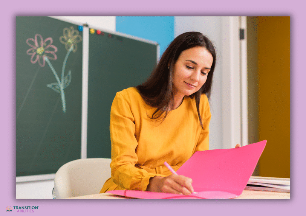 Teacher writing notes in pink folder at desk