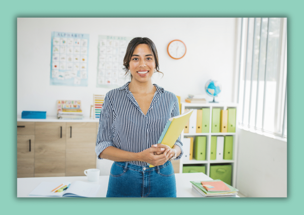 Teacher standing in organized classroom holding folders