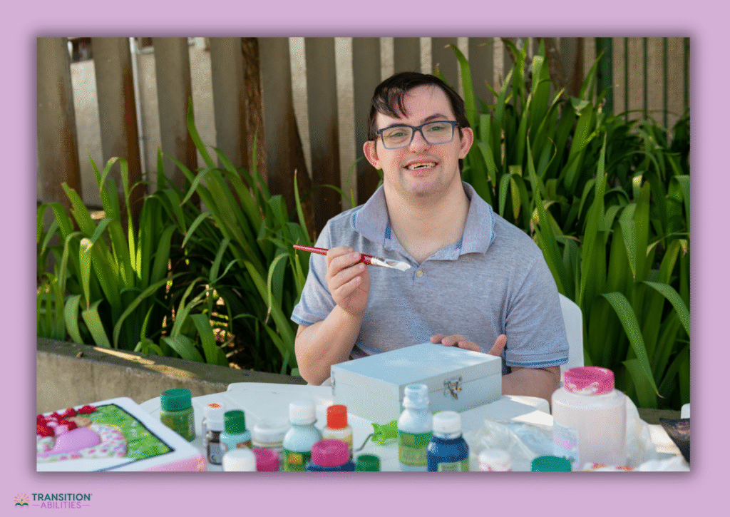 Young man painting craft box outdoors with art supplies