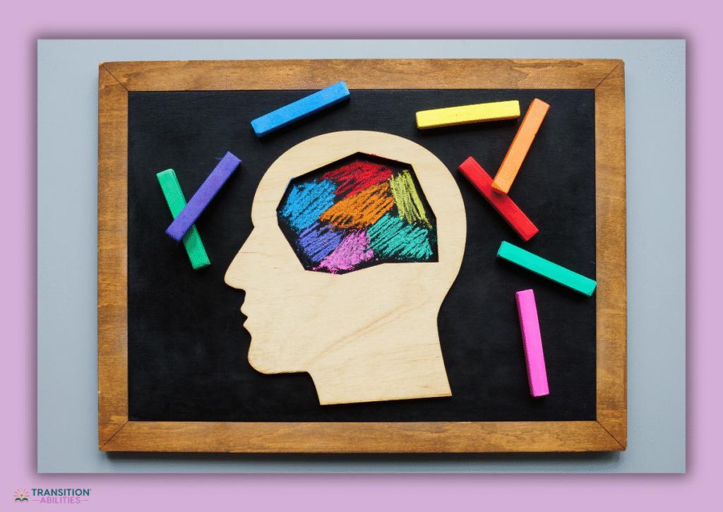 Wooden head silhouette with colorful brain drawing and chalk sticks