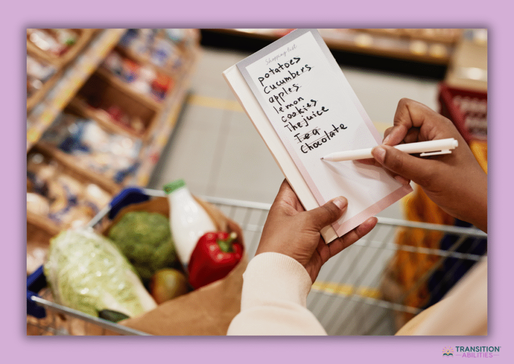 Person writing grocery list in store with shopping cart