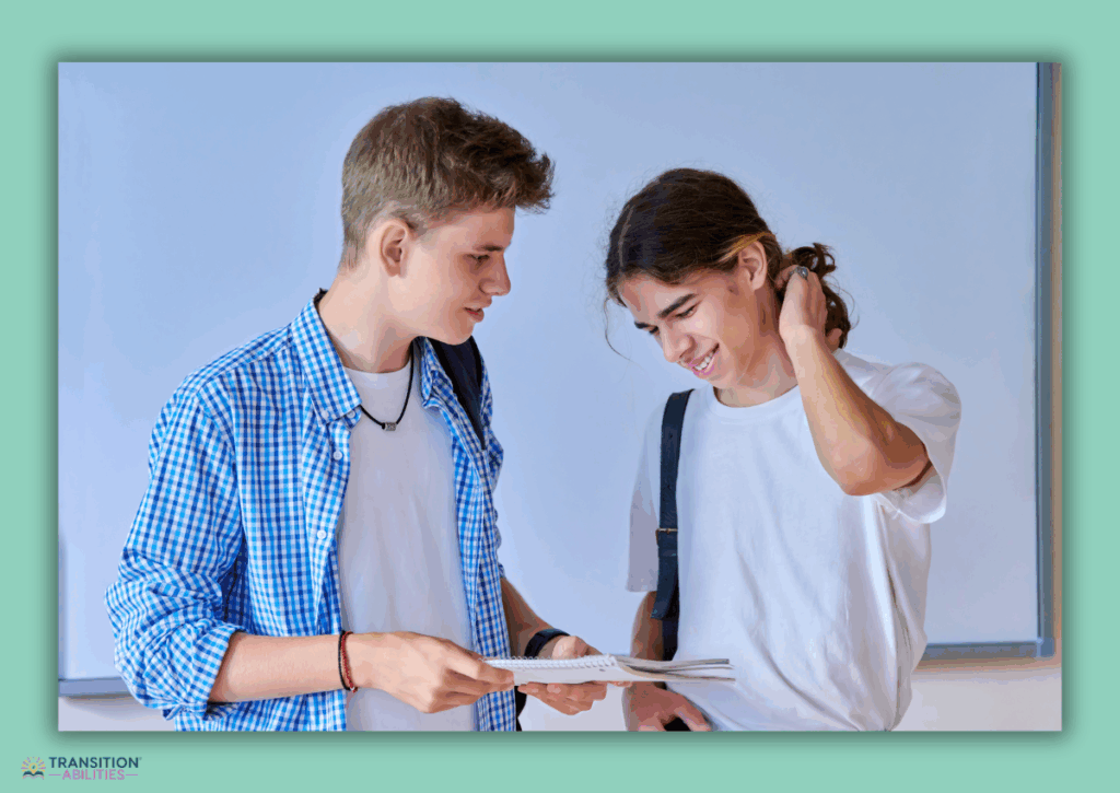 Two students talking while looking at a notebook