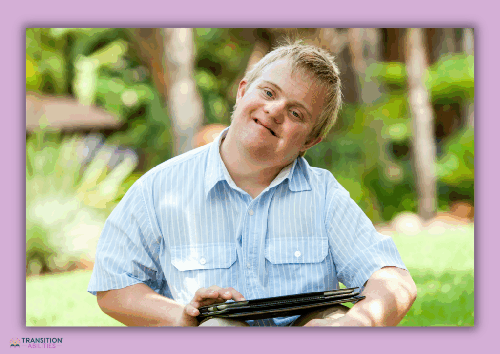 Young man with Down syndrome using a tablet outdoors