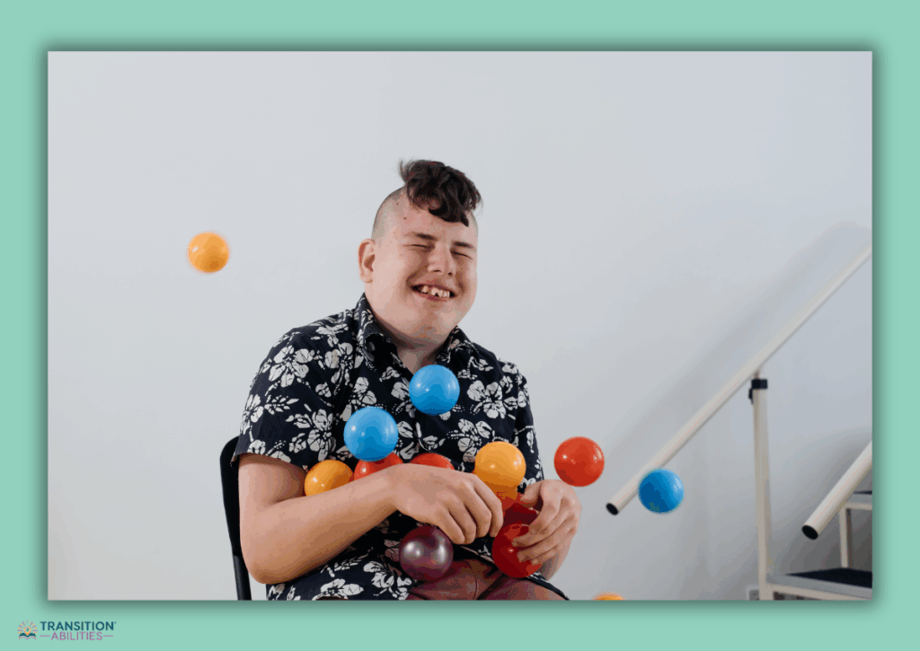 Smiling autistic person sitting with colorful balls around them.