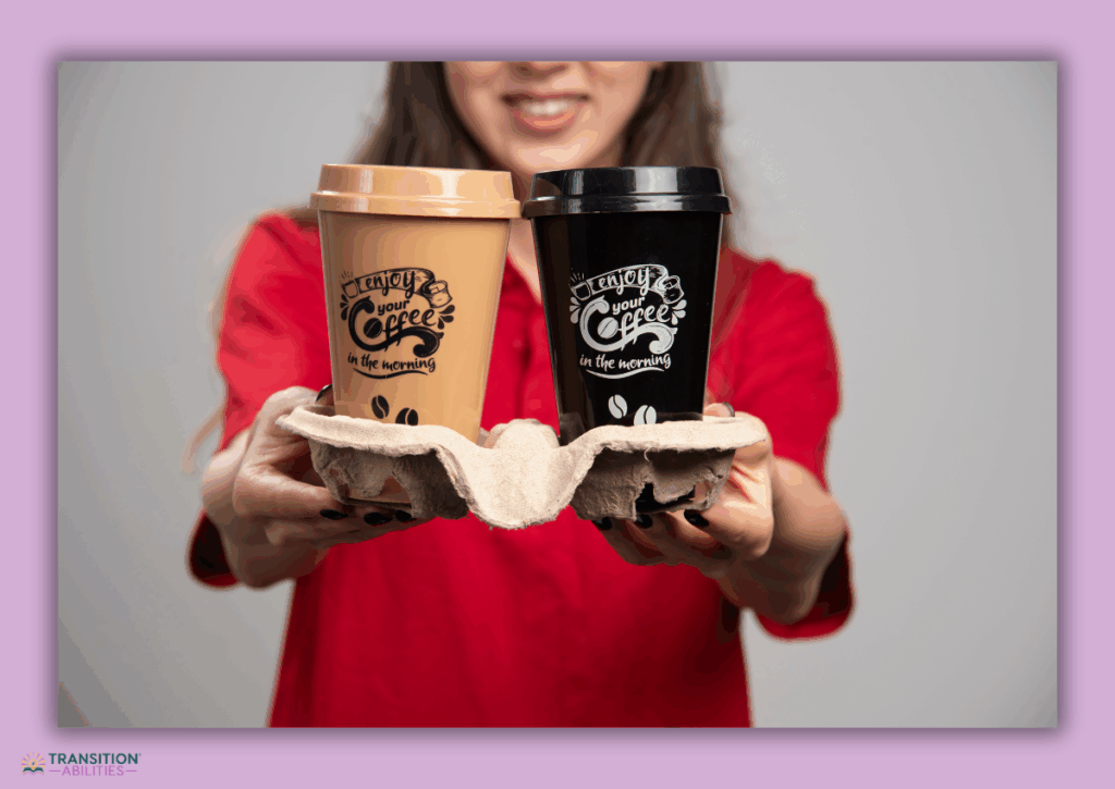 Person holding two takeaway coffee cups.