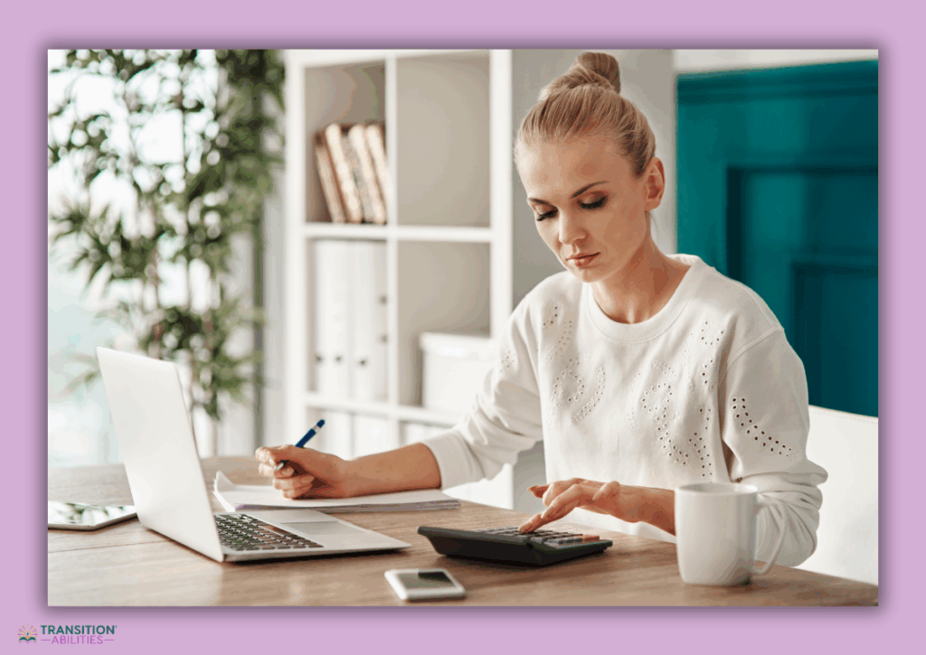 Adult working at a desk with a laptop and calculator.