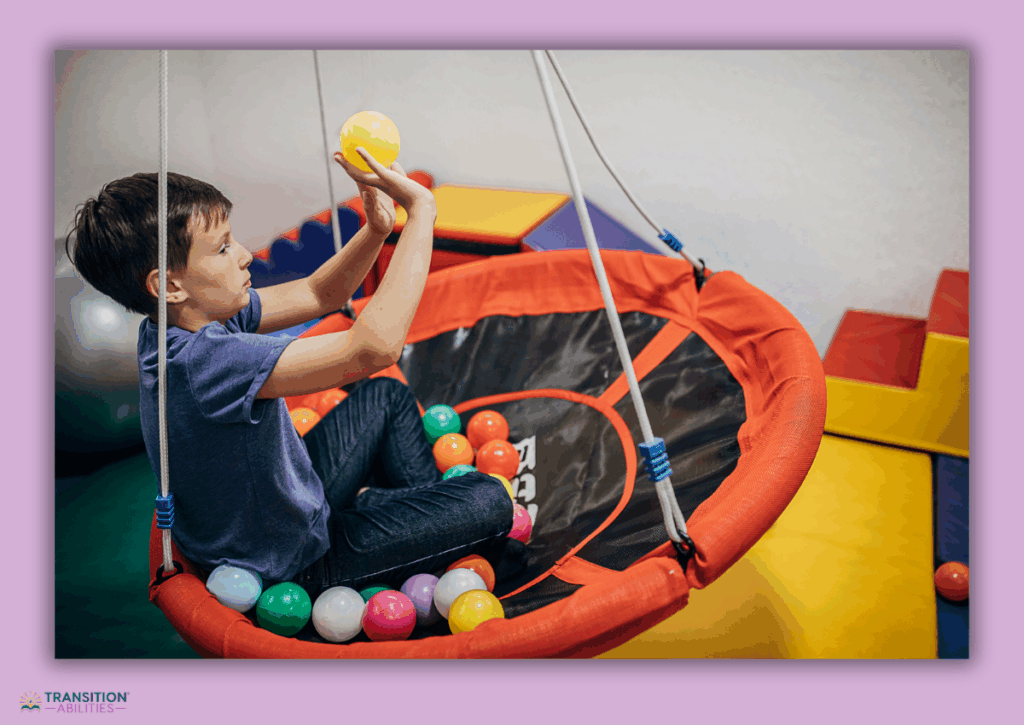 Child sitting in a swing playing with colorful balls.