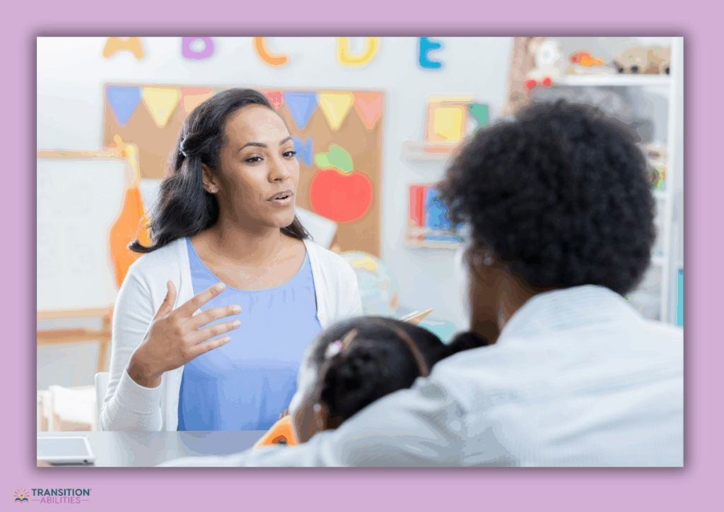 A teacher talks with a family during a meeting in a classroom.