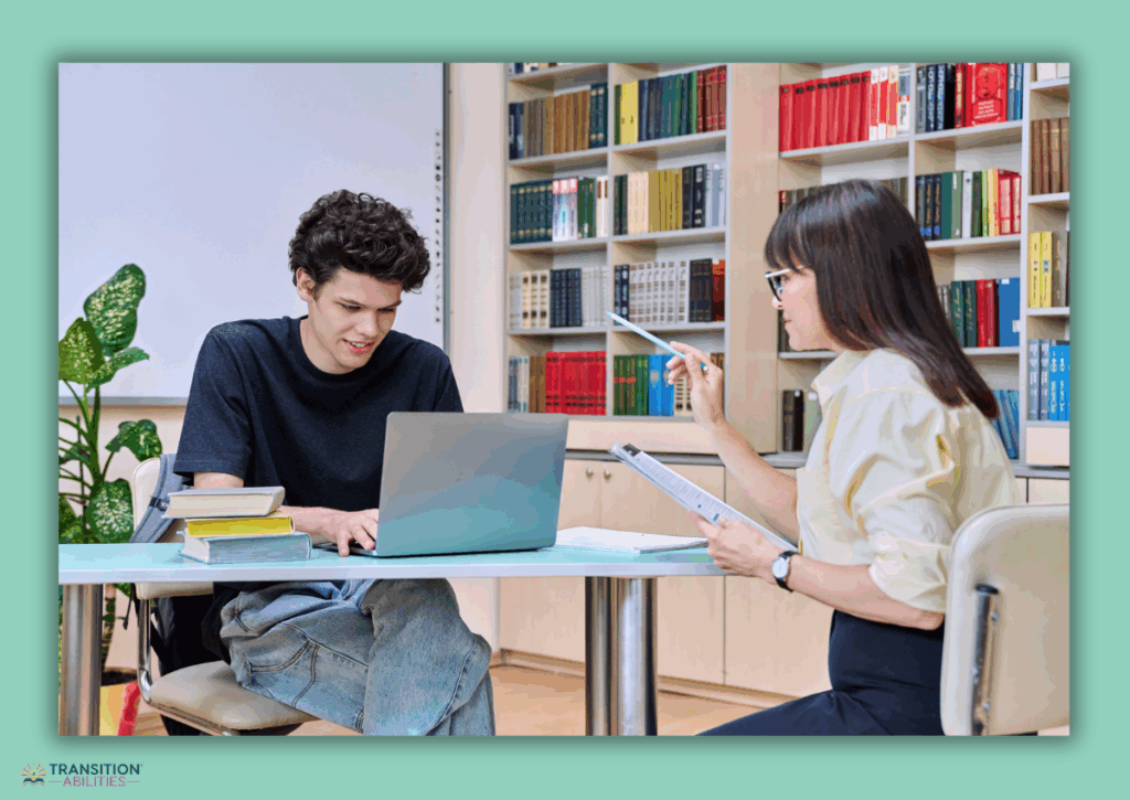 Teacher helping a student working on a laptop in a classroom.