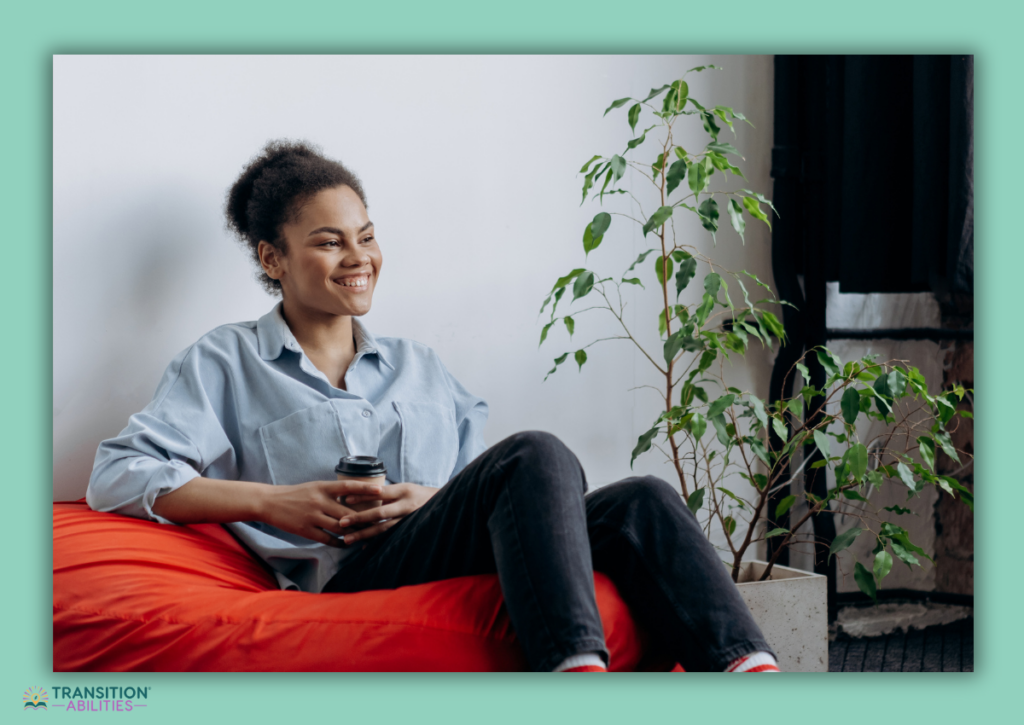 Teen girl smiling and relaxing on a red beanbag chair while holding a drink.
